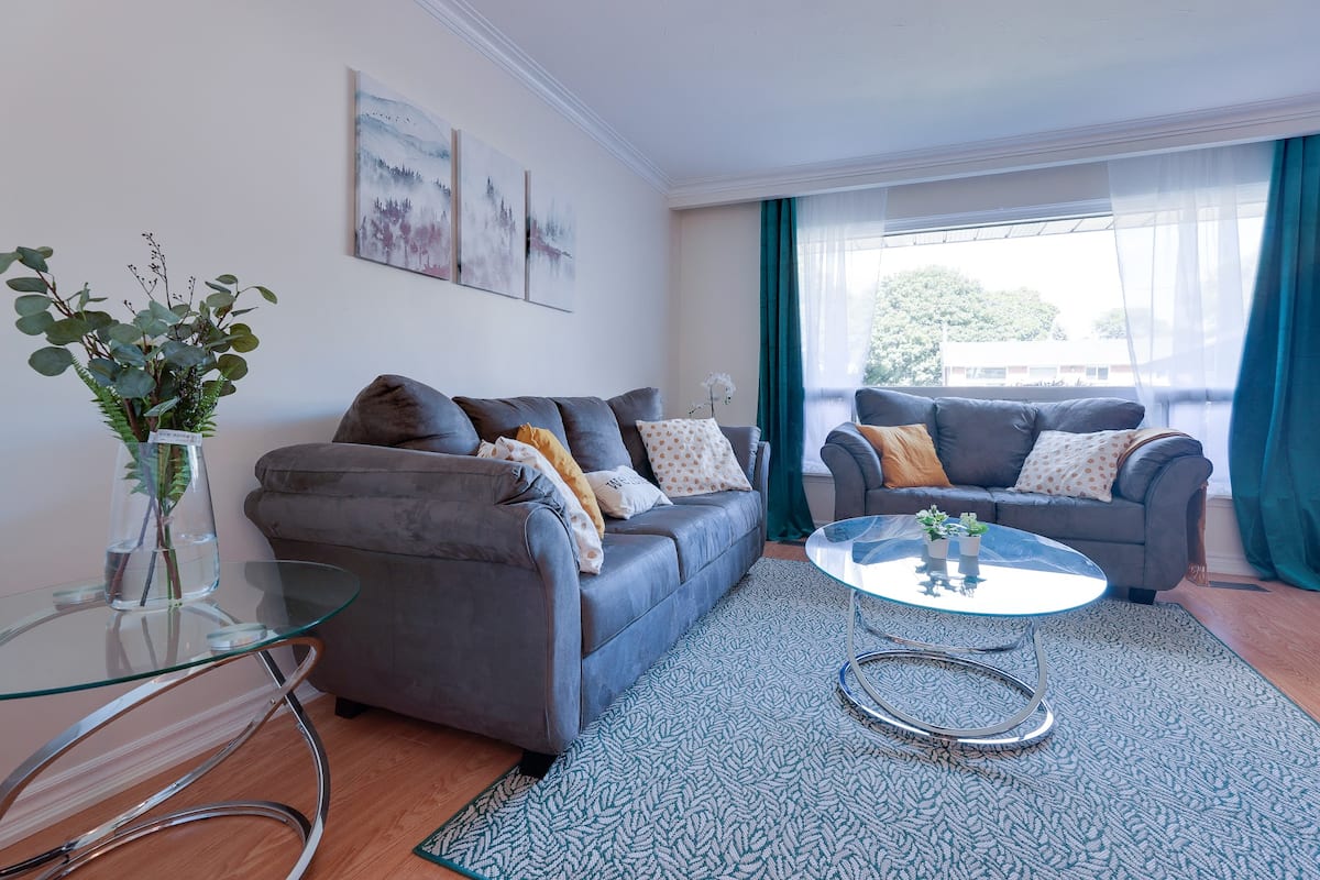 Bright living room with grey sofas, teal curtains and mustard cushions
